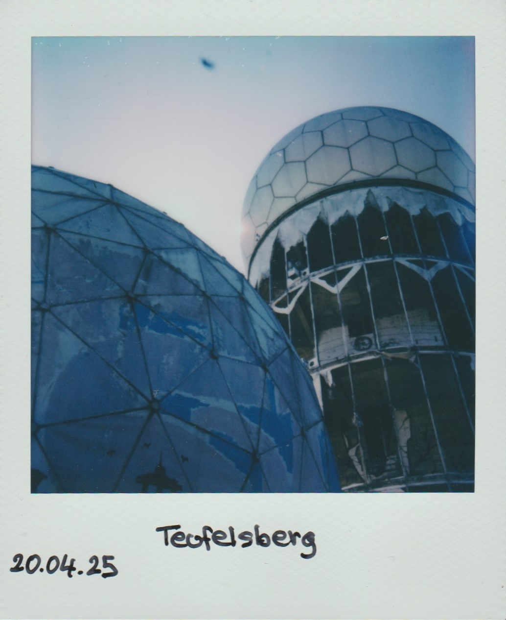 polaroid photo of two white domes. they are visibly run down.
